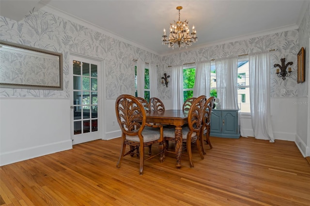 dining area with a notable chandelier, ornamental molding, and light hardwood / wood-style flooring