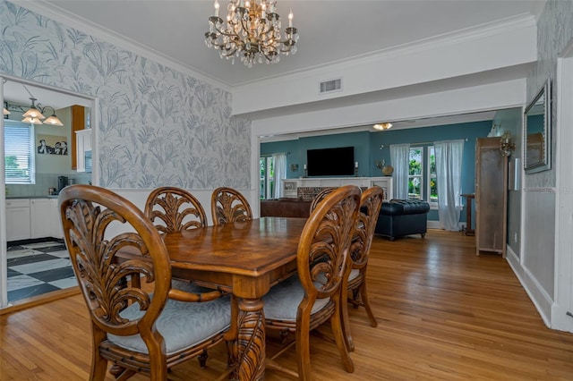 dining area featuring light hardwood / wood-style flooring, ornamental molding, and a chandelier