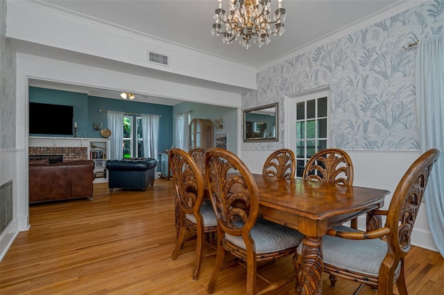 dining area with crown molding, a chandelier, and light wood-type flooring