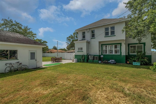 rear view of house featuring central AC unit, a lawn, and a patio