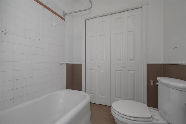 bathroom with toilet, a bathtub, and tile patterned flooring