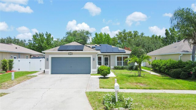 ranch-style house with solar panels, a garage, and a front yard