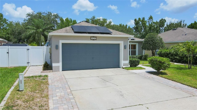 ranch-style house featuring a garage, a front lawn, and solar panels