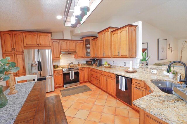 kitchen featuring light tile patterned floors, light stone counters, appliances with stainless steel finishes, and sink