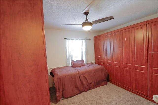 bedroom with light carpet, a textured ceiling, and ceiling fan