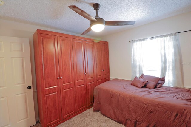 bedroom featuring a textured ceiling, ceiling fan, and light colored carpet