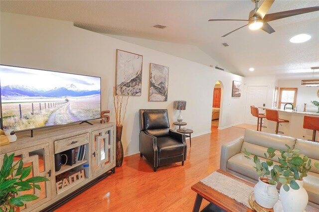 living room with ceiling fan, hardwood / wood-style flooring, and lofted ceiling