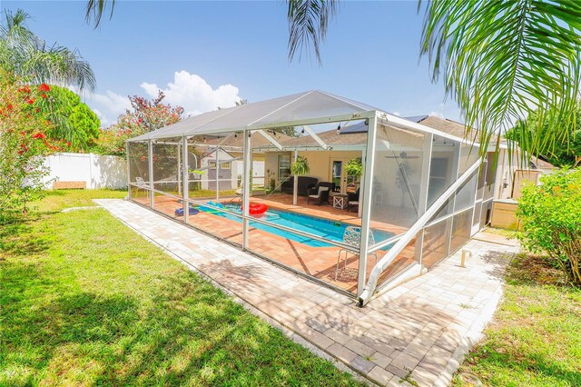 view of swimming pool with a lawn, a patio area, and a lanai