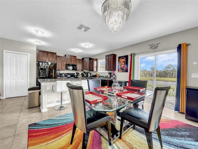 dining area featuring an inviting chandelier, light tile patterned floors, and a textured ceiling