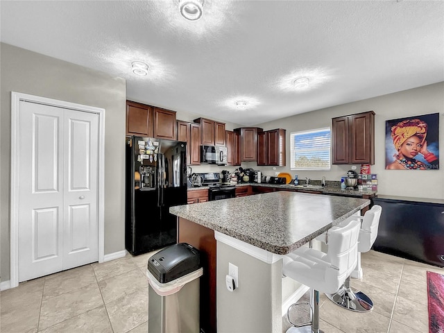 kitchen featuring black appliances, a kitchen island, a textured ceiling, and a kitchen bar