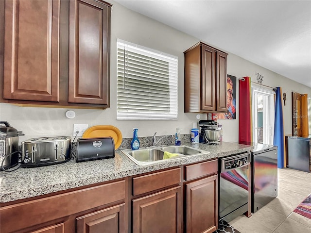 kitchen featuring dishwasher, sink, stainless steel refrigerator, and light tile patterned flooring