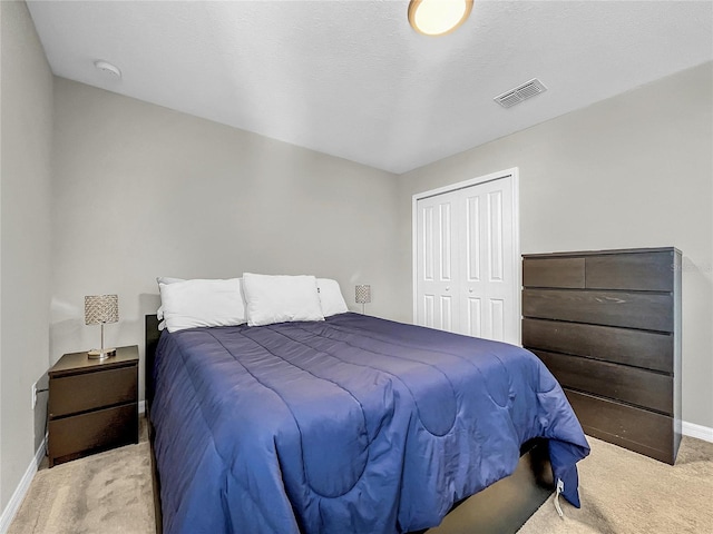 bedroom with a textured ceiling, light carpet, and a closet