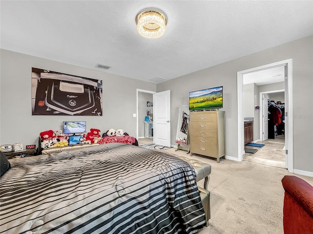 bedroom featuring connected bathroom, a textured ceiling, and light carpet