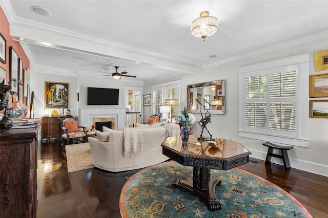 living room featuring dark wood-type flooring, a textured ceiling, ornamental molding, ceiling fan, and beam ceiling