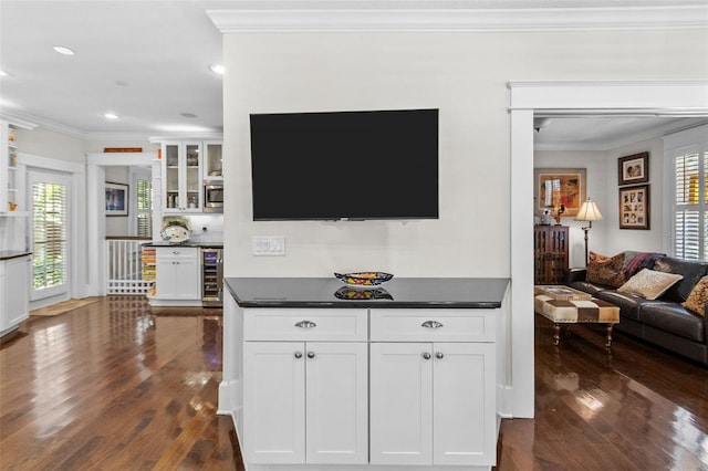 interior space with dark hardwood / wood-style flooring, ornamental molding, beverage cooler, and bar area