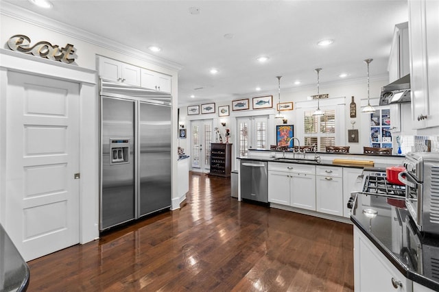 kitchen with sink, appliances with stainless steel finishes, white cabinetry, decorative light fixtures, and kitchen peninsula