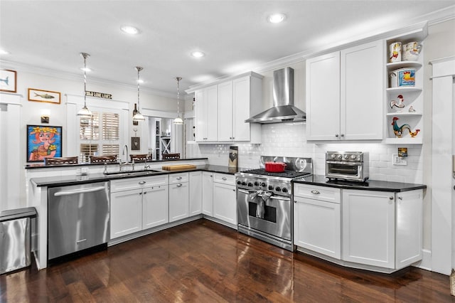 kitchen featuring hanging light fixtures, appliances with stainless steel finishes, wall chimney range hood, and white cabinets