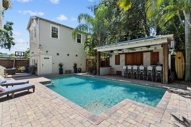 view of swimming pool featuring a patio, an outdoor structure, and a bar