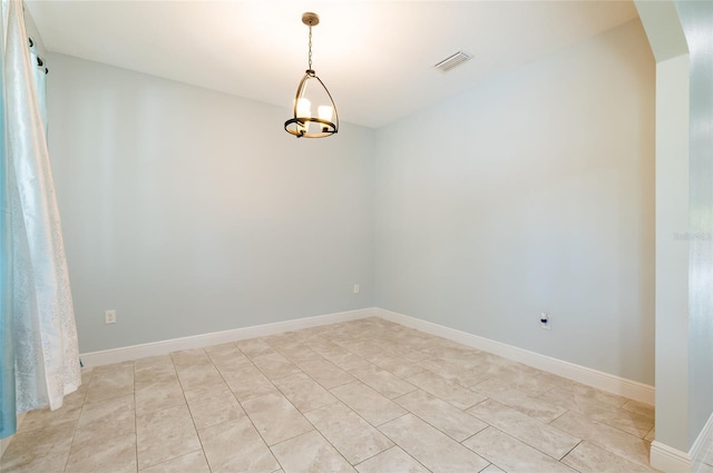 spare room with a chandelier and light tile patterned floors