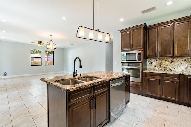 kitchen with sink, an island with sink, dark brown cabinets, and appliances with stainless steel finishes