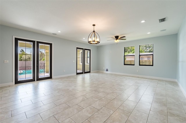 spare room featuring ceiling fan with notable chandelier, light tile patterned floors, and french doors