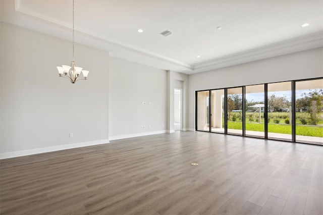 unfurnished room with a notable chandelier, hardwood / wood-style flooring, and a raised ceiling