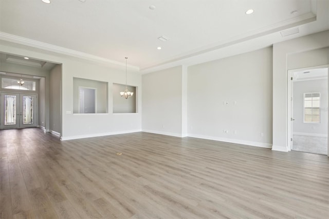 spare room with a notable chandelier, ornamental molding, hardwood / wood-style flooring, and french doors