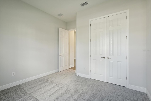 unfurnished bedroom featuring a closet and light colored carpet