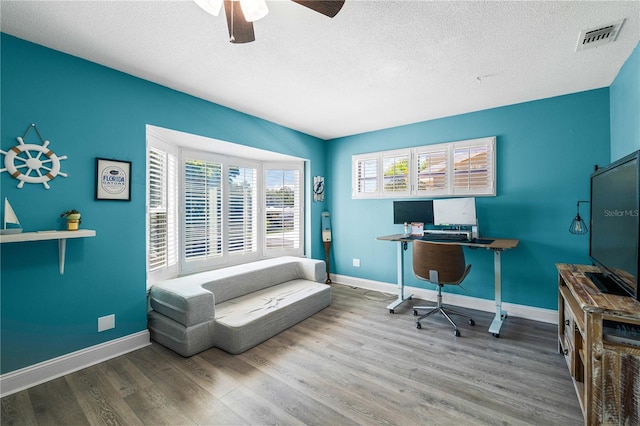 home office featuring ceiling fan, hardwood / wood-style flooring, and a textured ceiling