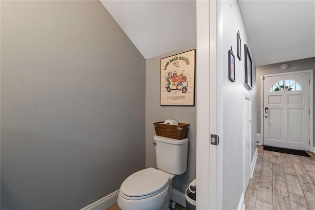 bathroom with lofted ceiling, hardwood / wood-style flooring, and toilet