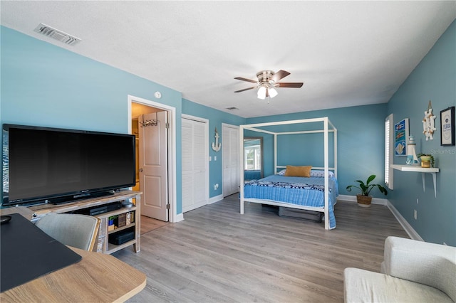 bedroom featuring multiple closets, ceiling fan, and hardwood / wood-style floors