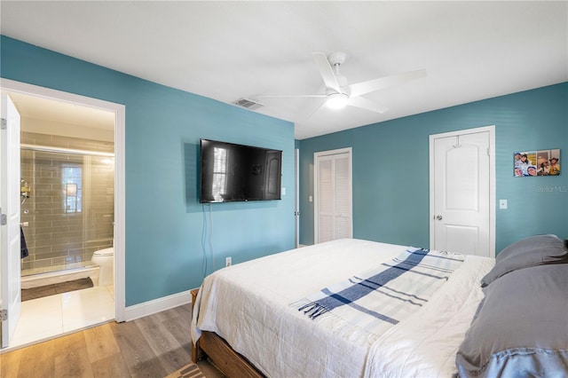 bedroom with multiple closets, ceiling fan, ensuite bathroom, and hardwood / wood-style floors