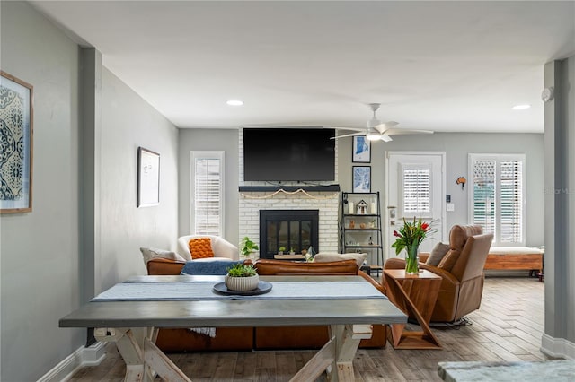 living room with a brick fireplace, hardwood / wood-style floors, and ceiling fan