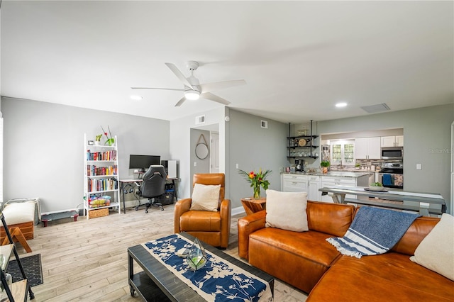 living room featuring ceiling fan and light hardwood / wood-style floors