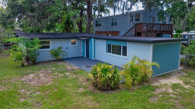 back of house with a deck and a lawn