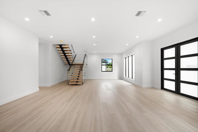 unfurnished living room with light wood-type flooring and french doors