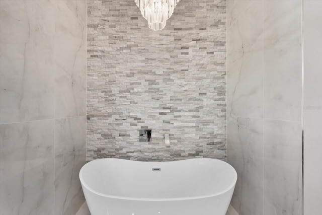 bathroom featuring a tub to relax in and an inviting chandelier