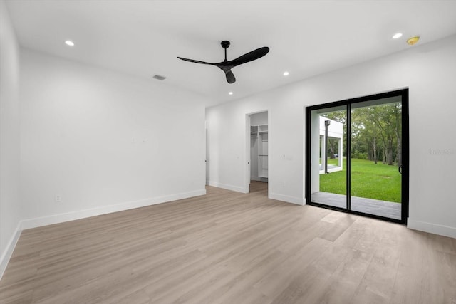 unfurnished bedroom with a spacious closet, access to exterior, a closet, light wood-type flooring, and ceiling fan