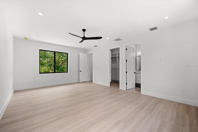 unfurnished bedroom with light hardwood / wood-style flooring, ceiling fan, ensuite bath, a walk in closet, and a closet