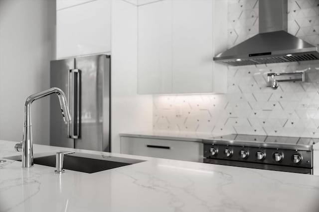 kitchen with white cabinets, wall chimney range hood, and light stone counters