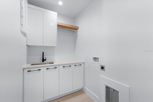 laundry area with cabinets, washer hookup, sink, hookup for an electric dryer, and light wood-type flooring