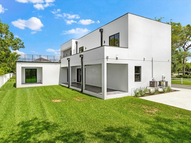 back of property with central air condition unit, a patio, and a lawn