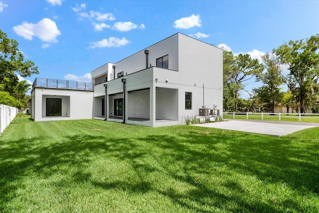 rear view of house with a patio, cooling unit, and a yard