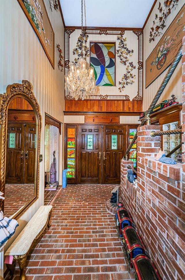 foyer entrance with an inviting chandelier, a towering ceiling, crown molding, and wood walls