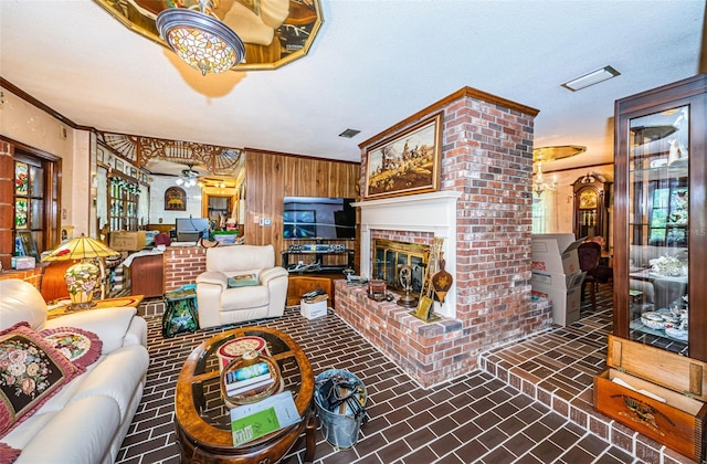 living room with crown molding, wooden walls, and a fireplace