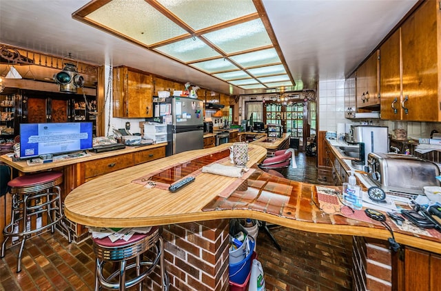 kitchen with a kitchen breakfast bar and stainless steel refrigerator