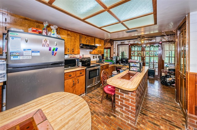 kitchen featuring stainless steel appliances and wood walls