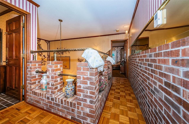 interior space featuring crown molding, brick wall, and dark parquet flooring