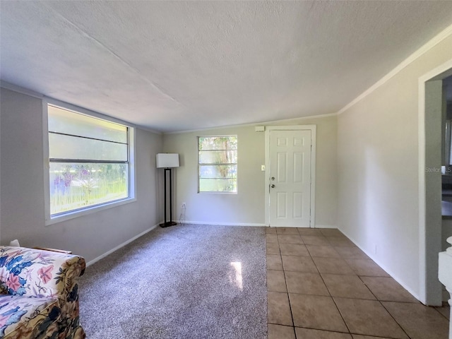 entryway with tile patterned flooring, ornamental molding, and a textured ceiling