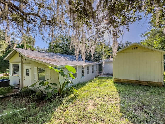 exterior space featuring central AC unit, a lawn, and a storage unit